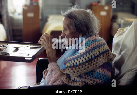 Eine ältere Patientin trägt einen gehäkelten Schal von ihrem Nachttisch in einer Krankenstation in Wales UK KATHY DEWITT sitzen Stockfoto