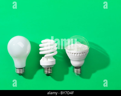 Drei Generationen von Glühbirnen. Regelmäßige Glühlampe, energiesparende Leuchtstofflampen und LED isoliert auf grünem Hintergrund Stockfoto