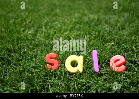Der Wort "Verkauf" dargelegt in bunten Buchstaben aus Kunststoff, auf dem grünen Rasen, genommen aus einem niedrigen Winkel Stockfoto
