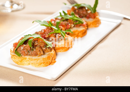 frische Tipycal italienische Bruschetta mit Tomaten und Rucola obenauf Stockfoto