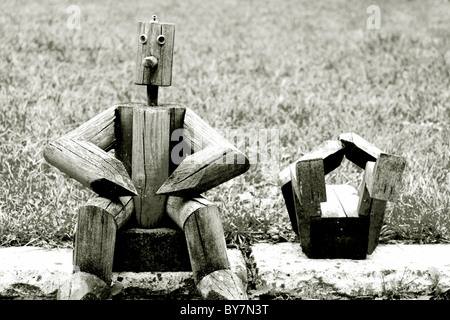 Holzfiguren sitzen in der Nähe von Wiese im Garten Stockfoto