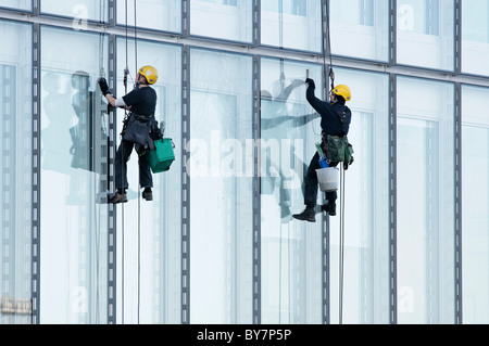 Zwei Fensterputzer hängt an Seilen, Reinigung der Fenster von BBC Scotland Büros, Pacific Quay, Glasgow, Schottland, Großbritannien. Stockfoto