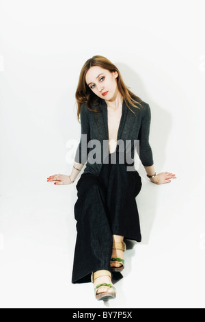 Studio-Porträt einer jungen blonden hübschen Frau auf dem Boden sitzend Stockfoto