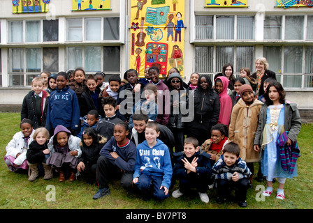 Gemischtes Alter junior School Kinder versammelten sich vor Schule Wandgemälde, die sie gemacht haben. Stockfoto