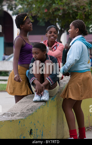 Kuba, Havanna. Afro-kubanischen Mädchen reden in einem Park. Die gelben Röcke identifizieren sie als Schülerinnen und Schüler. Stockfoto