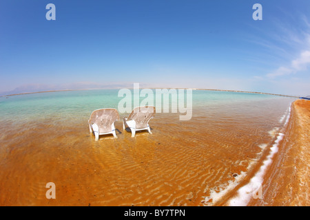 Zwei weiße Strandkörbe standen nebeneinander in das klare Wasser am Strand. Totes Meer, Israel Stockfoto