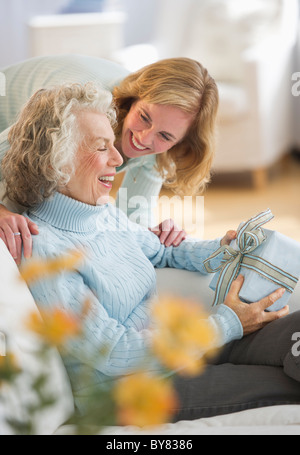 USA, New Jersey, Jersey City, Senior Frau empfangen präsentieren von Tochter auf sofa Stockfoto