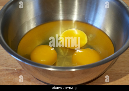 drei Eiern in eine Rührschüssel Metall gebrochen Stockfoto