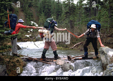 Wanderer / Backpackers helfen einander provisorischen Brücke über Mountain Creek in der Nähe von Pemberton, BC, Britisch-Kolumbien, Kanada Stockfoto