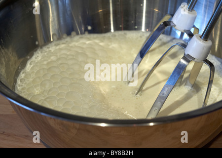 Frische Schlagsahne Sahne in eine Rührschüssel mit elektrischen Schneebesen Metall Stockfoto