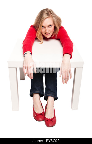 Junge Frau, Büroangestellter oder Student an lustigen kleinen Schreibtisch sitzen. Studio Foto, isoliert. Stockfoto