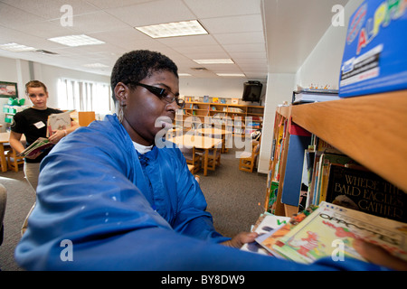 Freiwillige organisieren Sie Bücher in der Schulbibliothek Stockfoto