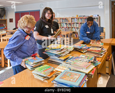 Freiwillige organisieren Sie Bücher in der Schulbibliothek Stockfoto