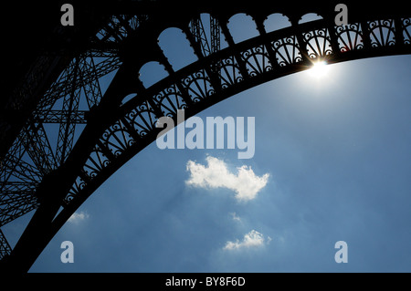 Die Sonne scheint durch den Bogen des Eiffelturms in Paris Stockfoto