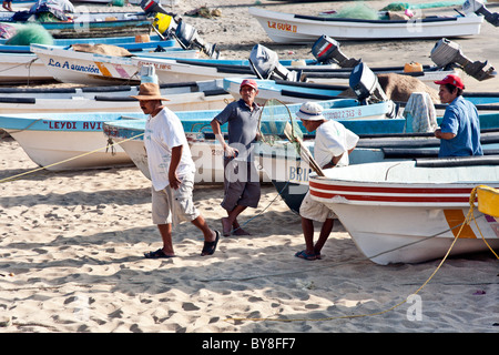 Fischer im Chat entspannende unter dicht gepackten gestrandeter Angelboote/Fischerboote am Ende des Nachmittags in Puerto Angel Oaxaca Staat Mexiko Stockfoto