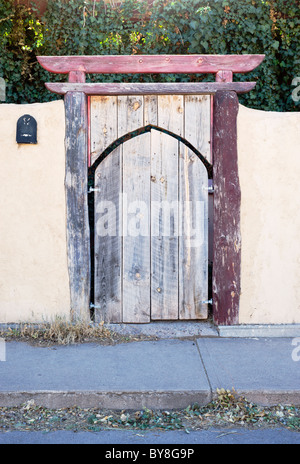 Ein verblassen Holz Tor eingelassen ein Adobe-Wand gefunden in Tularosa, New Mexico. Stockfoto