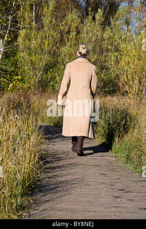 RÜCKANSICHT EINER FRAU ZU FUß IN DIE LANDSCHAFT IM WINTER Stockfoto