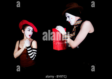 Mann-Mime verleiht der Frau Geschenk im roten Feld Stockfoto