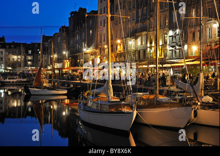 Segelboote und Touristen an Straßencafés / Bürgersteig Cafés entlang des Kais der Honfleur Hafen bei Nacht, Normandie, Frankreich Stockfoto