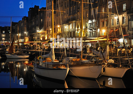 Segelboote und Touristen an Straßencafés / Bürgersteig Cafés entlang des Kais der Honfleur Hafen bei Nacht, Normandie, Frankreich Stockfoto