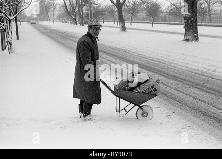 Alter Mann überquert die Stafford Road in Fordhouses, Wolverhampton mit seinem Einkaufen in einer Schubkarre bei starkem Schnee 9/2/1985 Großbritannien Winter 1985 BILD VON DAVID BAGNALL Stockfoto