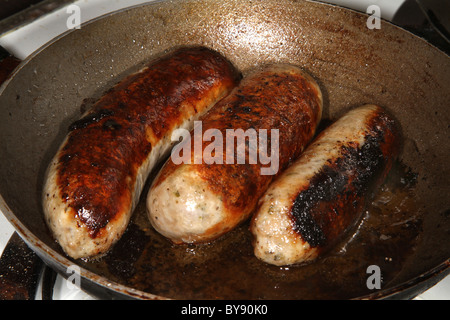 Drei große Lincolnshire Würstchen aus Schweinefleisch in der Pfanne kochen. Stockfoto