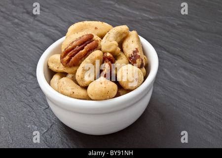 Gesalzene Nussmischung in Schüssel auf dunklen grauen Schiefer Hintergrund. Stockfoto