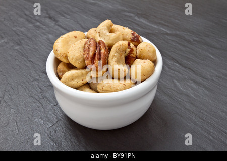 Gesalzene Nussmischung in Schüssel auf dunklen grauen Schiefer Hintergrund. Stockfoto