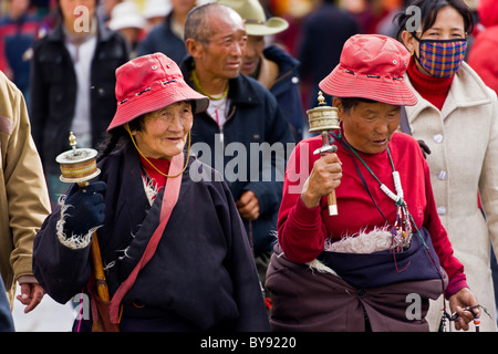 Zwei alte tibetische Frauen pilgern mit roten Hüten drehen Gebetsmühlen im Barkhor, Lhasa, Tibet. JMH4472 Stockfoto