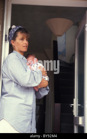 unglückliche Mutter stehend auf offene Tür hält ihr baby Stockfoto