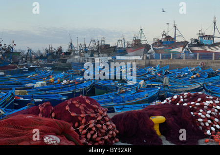 Blaue Angelboote/Fischerboote und roten Netze im frühen Morgengrauen in der Marine vor Anker Hafen von Essaouira Marokko mit großen Angelboote/Fischerboote Stockfoto