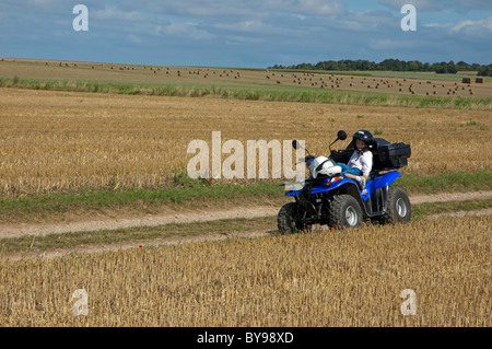 Vier Jahre altes Mädchen sitzen auf einem Quadbike geparkt in der Mitte einem abgeernteten Weizenfeld, Normandie, Frankreich. Stockfoto