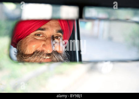 Sikh Taxifahrer Blick in den Rückspiegel Stockfoto