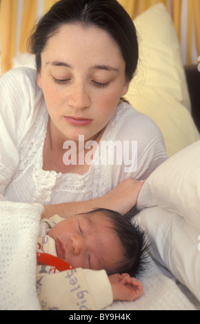 unglückliche junge Mutter Blick auf ihr neugeborenes Baby schlafen Stockfoto