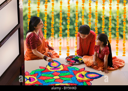 Frau macht ein Rangoli, während ihre Kinder beobachten Stockfoto