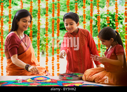 Frau macht ein Rangoli, während ihre Kinder beobachten Stockfoto