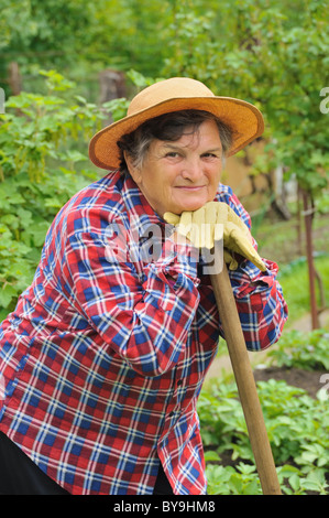 Ältere Frau Gartenarbeit - ruht auf ihre Hacke nach der Arbeit Stockfoto