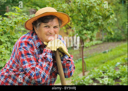 Ältere Frau Gartenarbeit - ruht auf ihre Hacke nach der Arbeit Stockfoto