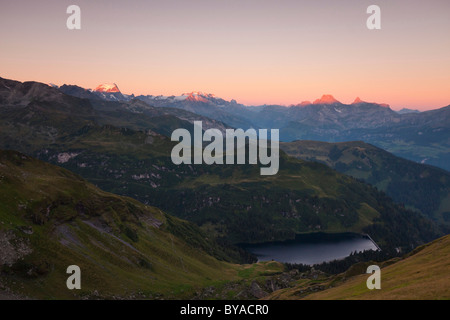 Ersten Sonnenstrahlen auf den Gipfeln der Glarner Alpen mit Garichti-Stausee im Tal, gesehen vom Berglimatt, Kanton Glarus Stockfoto