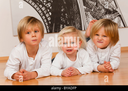 2 Jungs, 7 und 4 Jahre und ein Mädchen, 1,5 Jahre, auf dem Boden liegend Stockfoto