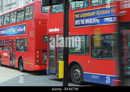 Teile von zwei roten Londoner Busse in Oxford Circus, London, England mit einem unscharfen Teil eines dritten bus, wie es geht auf der Innenseite Stockfoto