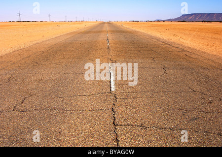 Endlose Asphaltstraße schnurgeraden durchquert die Wüste Bereich in der Nähe von Al Awaynat, Libyen, Nordafrika Stockfoto
