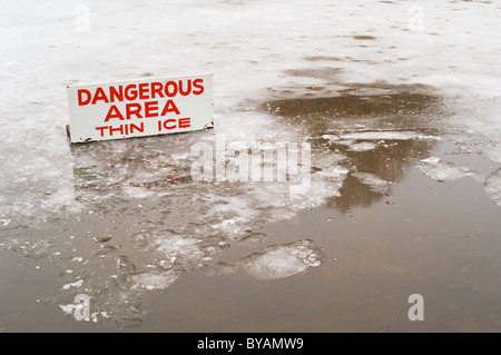 Ein Teich abgedeckt in einer dünnen Schicht aus Eis mit einigen open Water und ein Zeichen der Gefahr bedeutet. Stockfoto