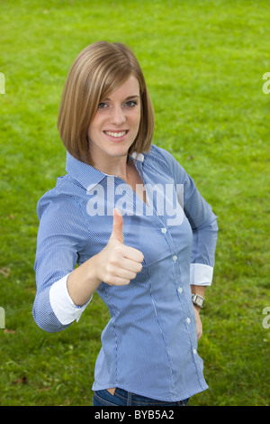 Junge Frau, die ein Daumen hoch, Lächeln Stockfoto