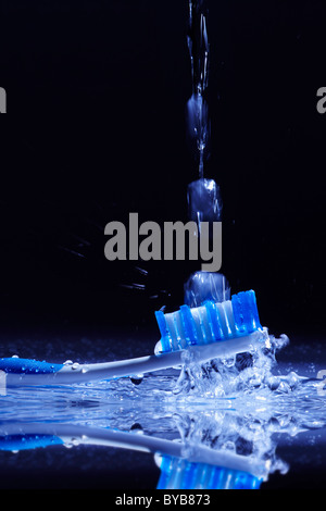 Blaue und weiße Zahnbürste mit einem Wasserstrahl gereinigt wird Stockfoto