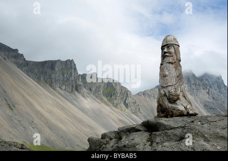 Kunst in der Landschaft, eine aus Holz geschnitzte Viking vor einem Bergrücken und Rocky Mount Vestrahorn, Stokknes in der Nähe von Hoefn, Island Stockfoto