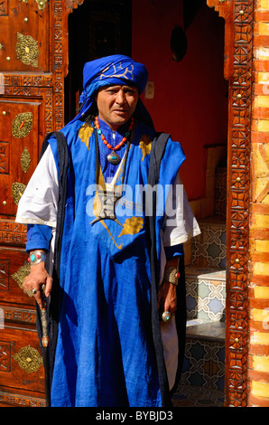 Mann in traditionellen Blau berber Gewandung in aufwändigen Einlegearbeiten aus Holz geschnitzte Tür Marrakesch Marokko Stockfoto