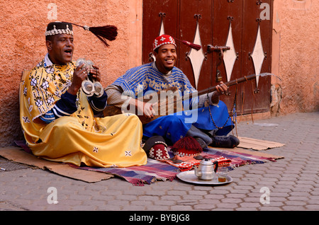 Glückliches Paar gnawa Straßenmusikanten spielen und hajhuj krakeb in Marrakesch ihre Tarboosh Quasten in der Zeit Schwingen zur Musik Marokko Stockfoto