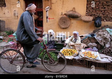 Ein ägyptischer Mann auf einem Fahrrad im Gespräch mit Männern Verkauf von Obst und Gemüse in einer Straße in Ägypten Stockfoto