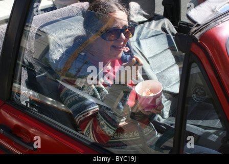 Ältere Frau genießt ein Eis-Genuss beim Sitzen in einem Auto. Stockfoto